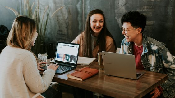 Studierende sitzen gemeinsam an einem Tisch und unterhalten sich