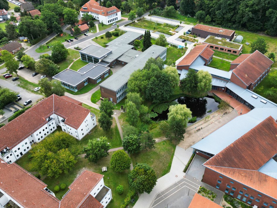 Luftbild des Campus Suderburg mit Blick auf Wohnheim, Teich und die Gebäude A bis G.