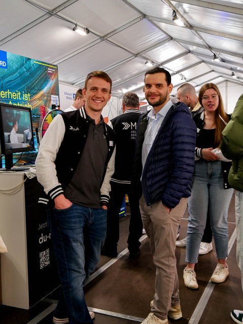 Messebesucher*innen am Info-Stand eines Unternehmens. 