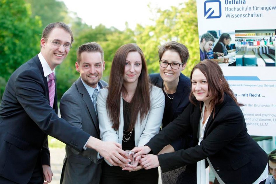Die Preisträgerinnen und Preisträger lächeln in die Kamera und und präsentieren gemeinsam einen Glasquader, der als Auszeichnung vergeben wurde.